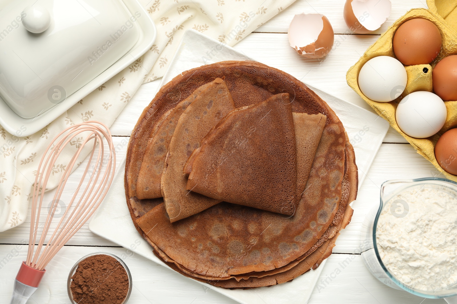 Photo of Delicious chocolate crepes and ingredients on white wooden table, flat lay