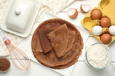 Photo of Delicious chocolate crepes and ingredients on white wooden table, flat lay