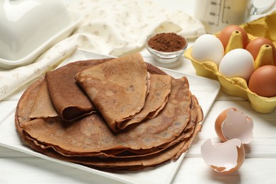 Photo of Delicious chocolate crepes and ingredients on white wooden table, closeup