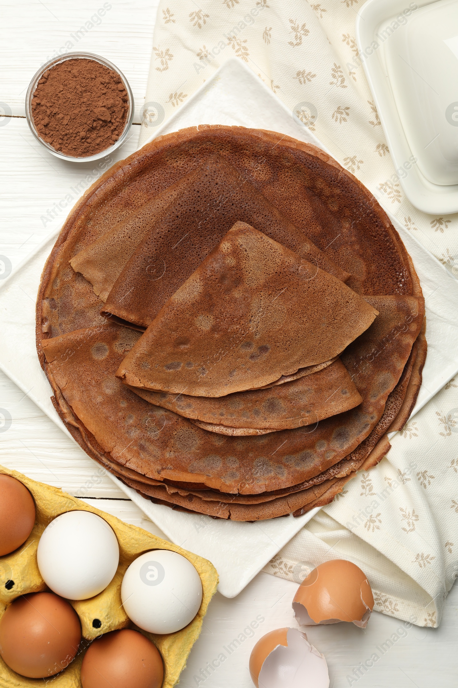 Photo of Delicious chocolate crepes and ingredients on white wooden table, flat lay