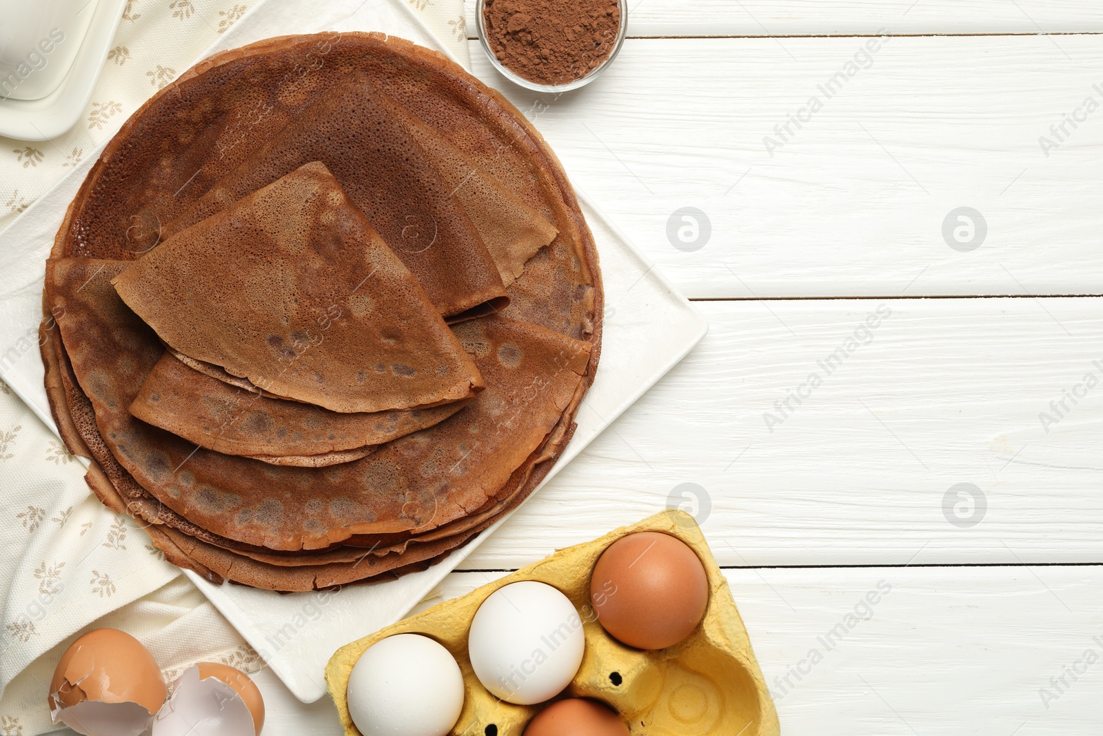 Photo of Delicious chocolate crepes and ingredients on white wooden table, flat lay. Space for text