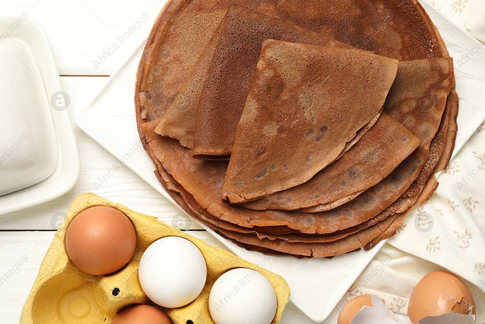 Photo of Delicious chocolate crepes and ingredients on white wooden table, flat lay