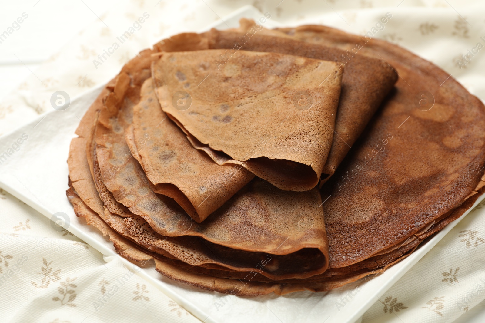 Photo of Stack of delicious chocolate crepes on table, closeup