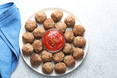 Photo of Delicious meatballs with ketchup and spices on light textured table, flat lay