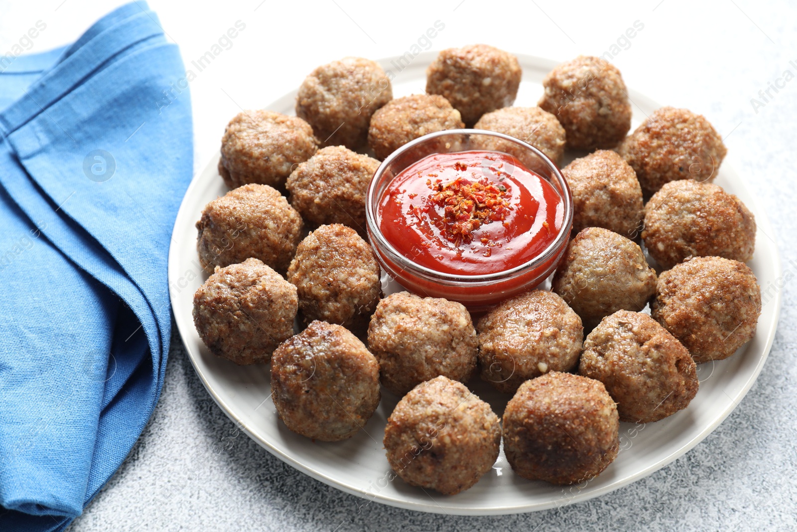 Photo of Delicious meatballs with ketchup and spices on light textured table, closeup