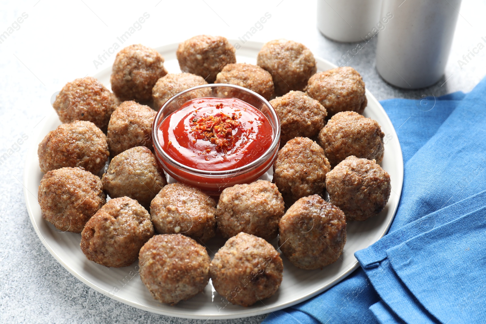 Photo of Delicious meatballs with ketchup and spices on light textured table, closeup