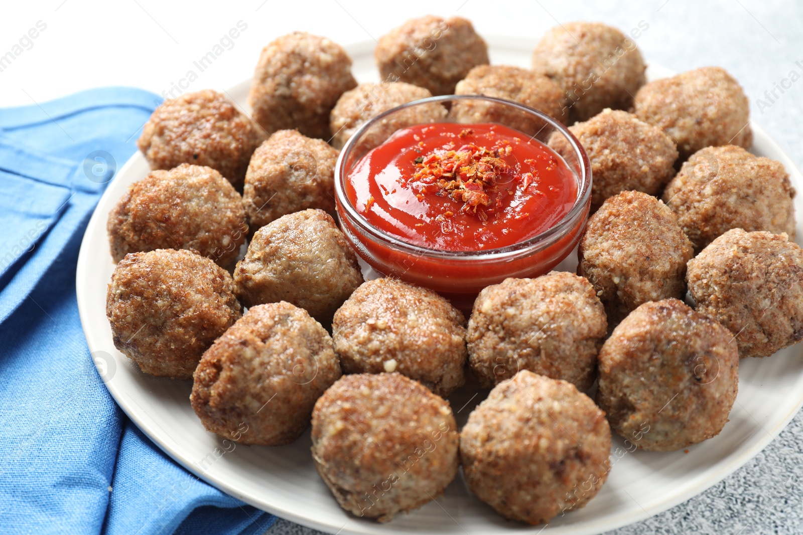 Photo of Delicious meatballs with ketchup and spices on light textured table, closeup