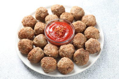 Photo of Delicious meatballs with ketchup and spices on light textured table, closeup