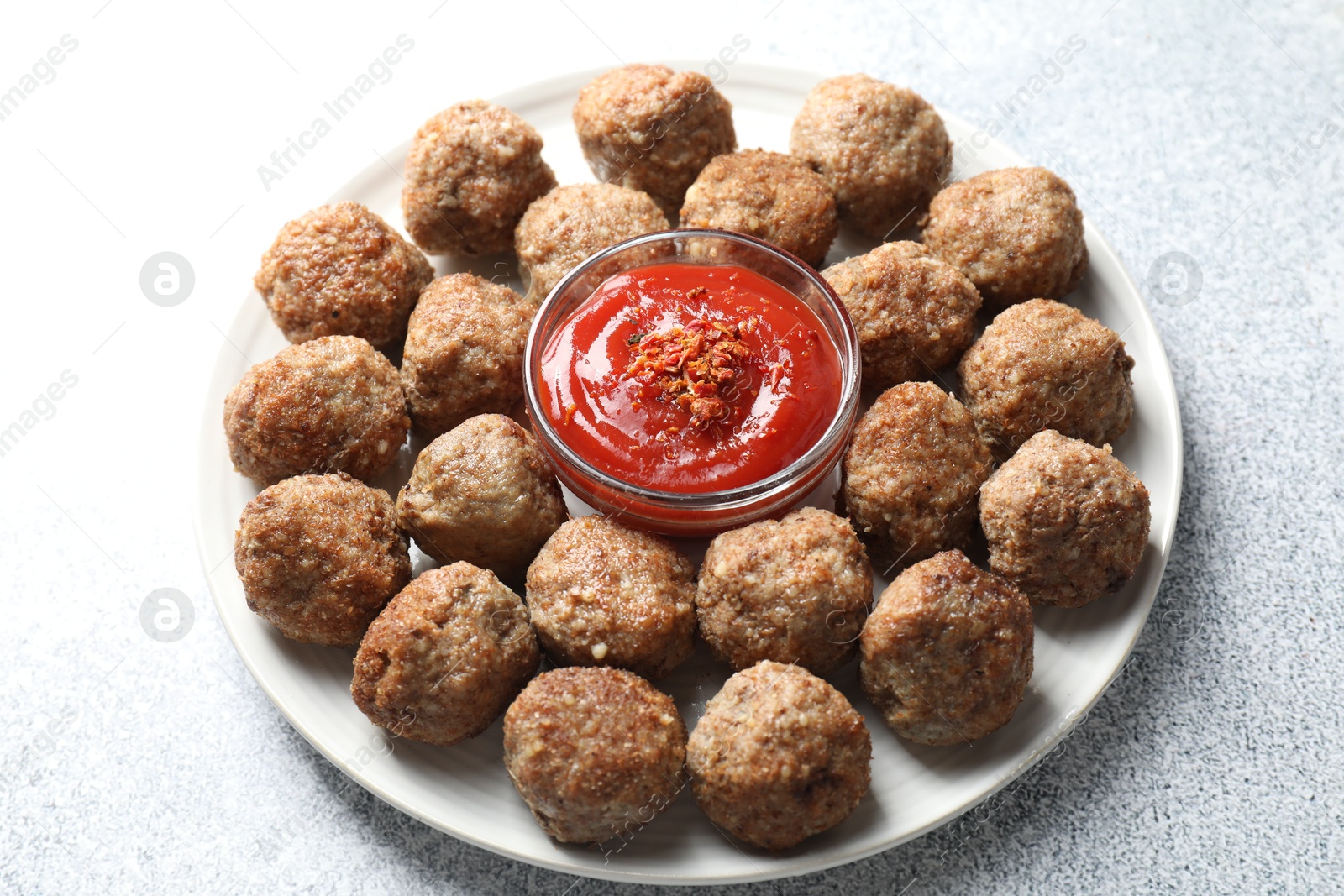 Photo of Delicious meatballs with ketchup and spices on light textured table, closeup