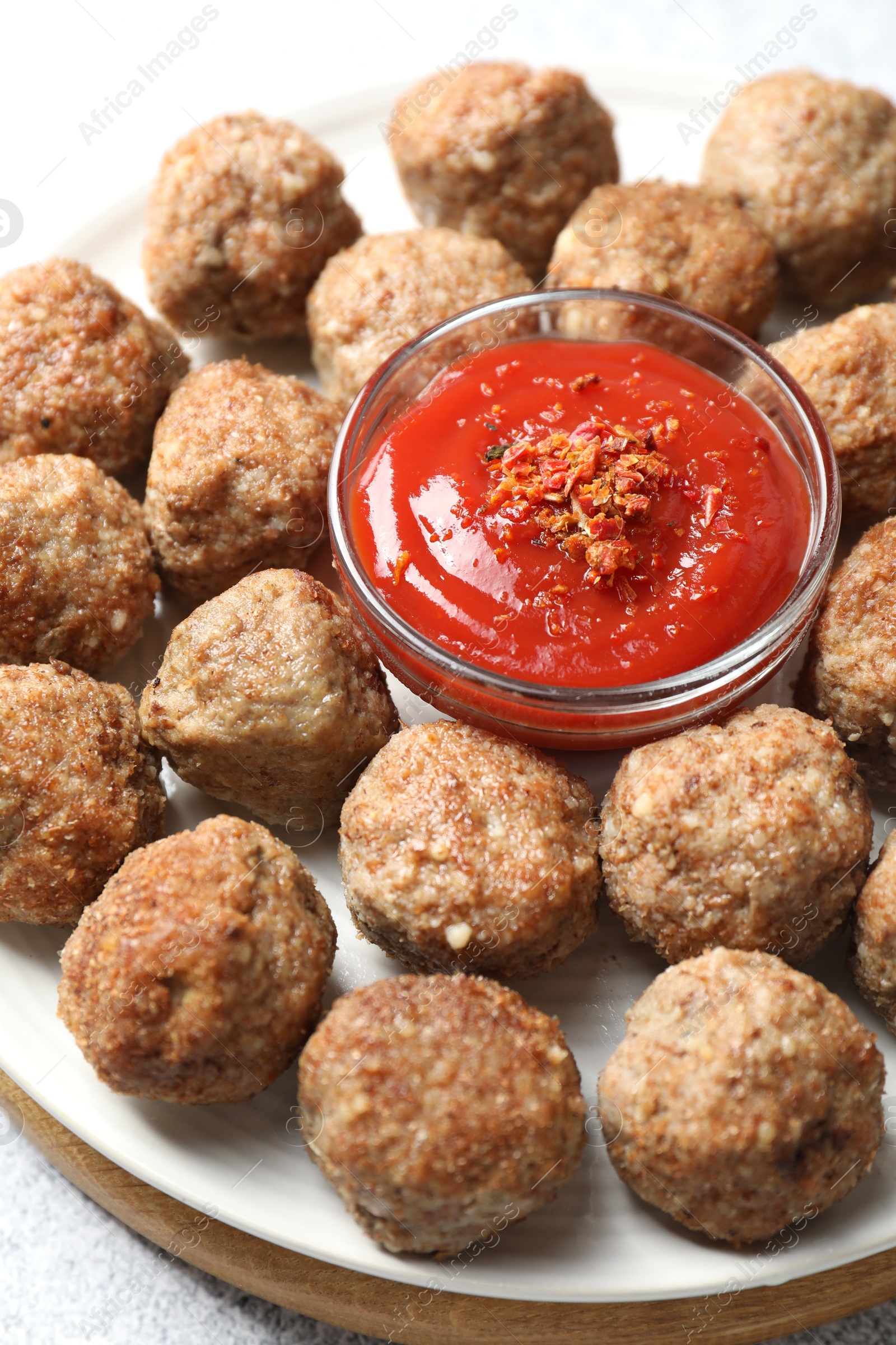 Photo of Delicious meatballs with ketchup and spices on light table, closeup