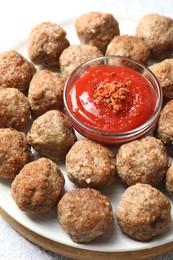 Photo of Delicious meatballs with ketchup and spices on light table, closeup