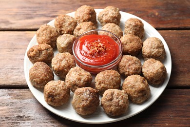 Photo of Delicious meatballs with ketchup and spices on wooden table, closeup