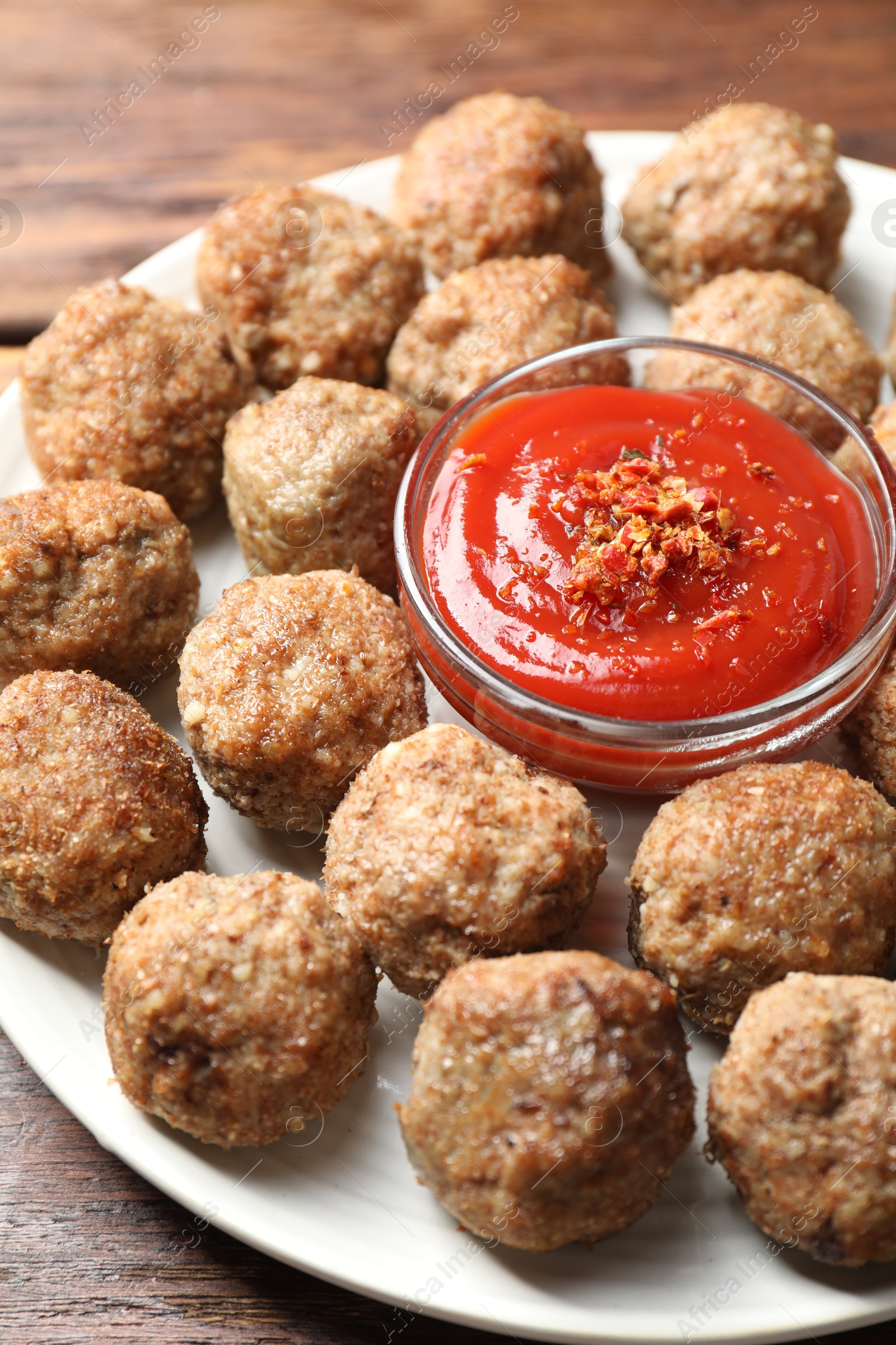 Photo of Delicious meatballs with ketchup and spices on wooden table, closeup