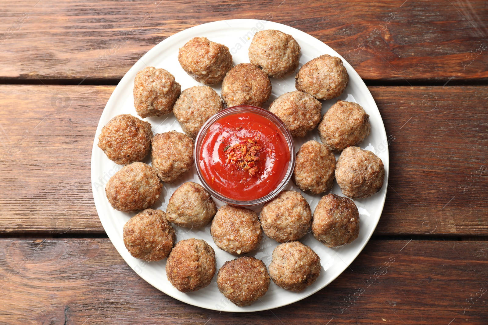 Photo of Delicious meatballs with ketchup and spices on wooden table, top view