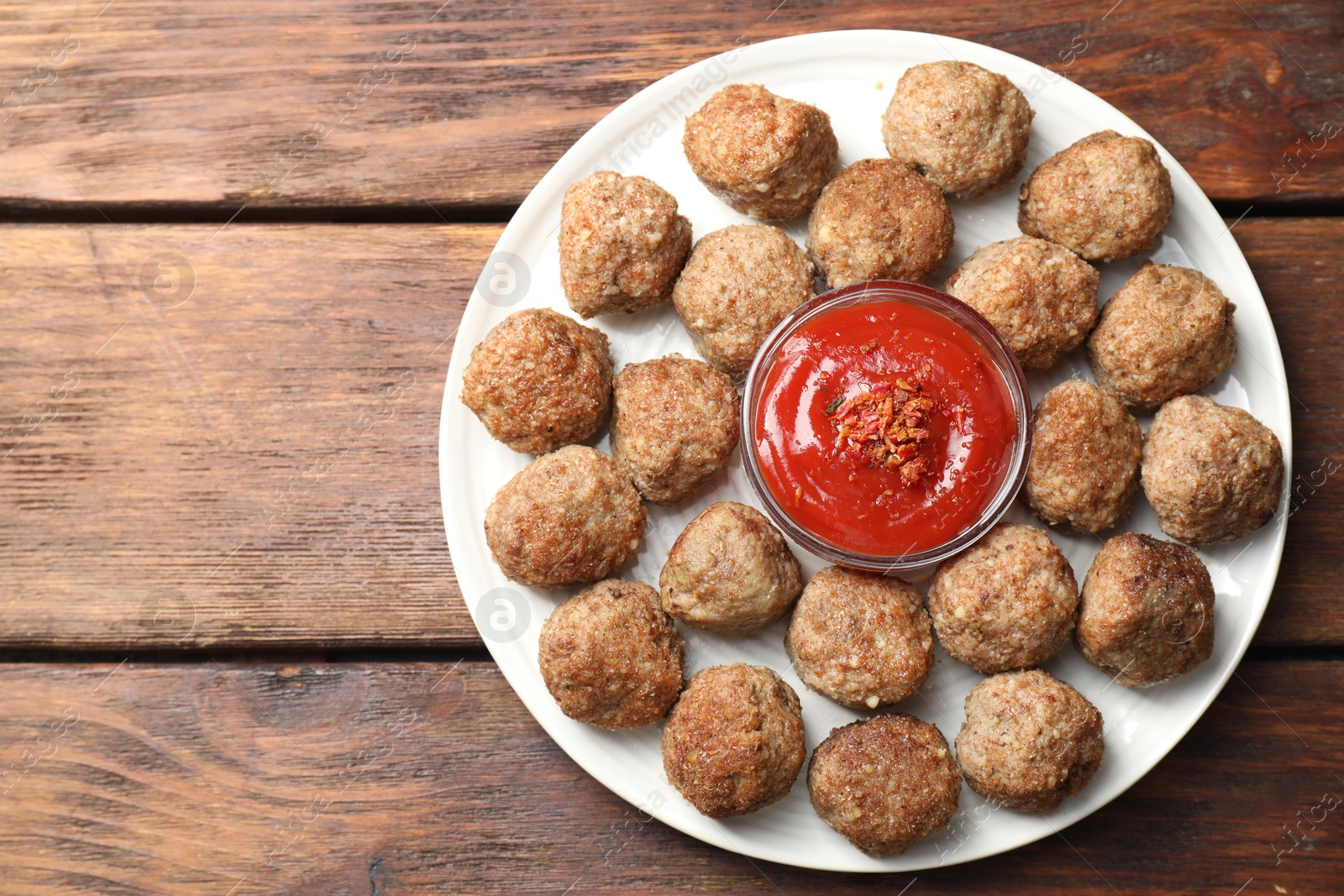 Photo of Delicious meatballs with ketchup and spices on wooden table, top view. Space for text