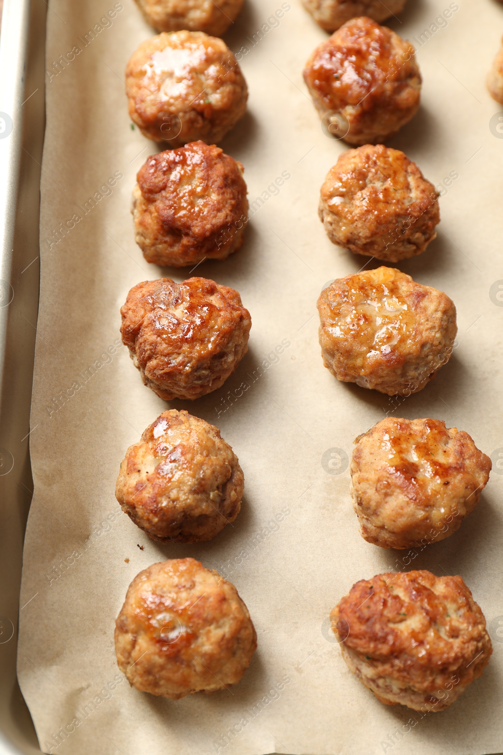 Photo of Many delicious meatballs on parchment in baking dish, above view