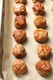 Photo of Many delicious meatballs on parchment in baking dish, above view