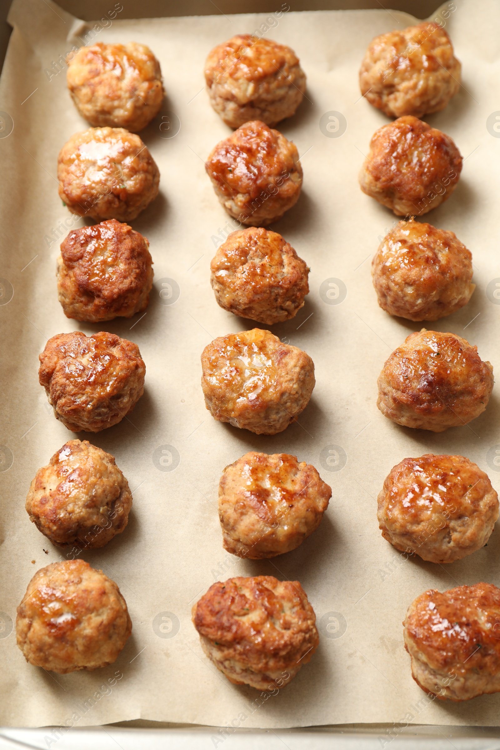 Photo of Many delicious meatballs on parchment in baking dish, above view