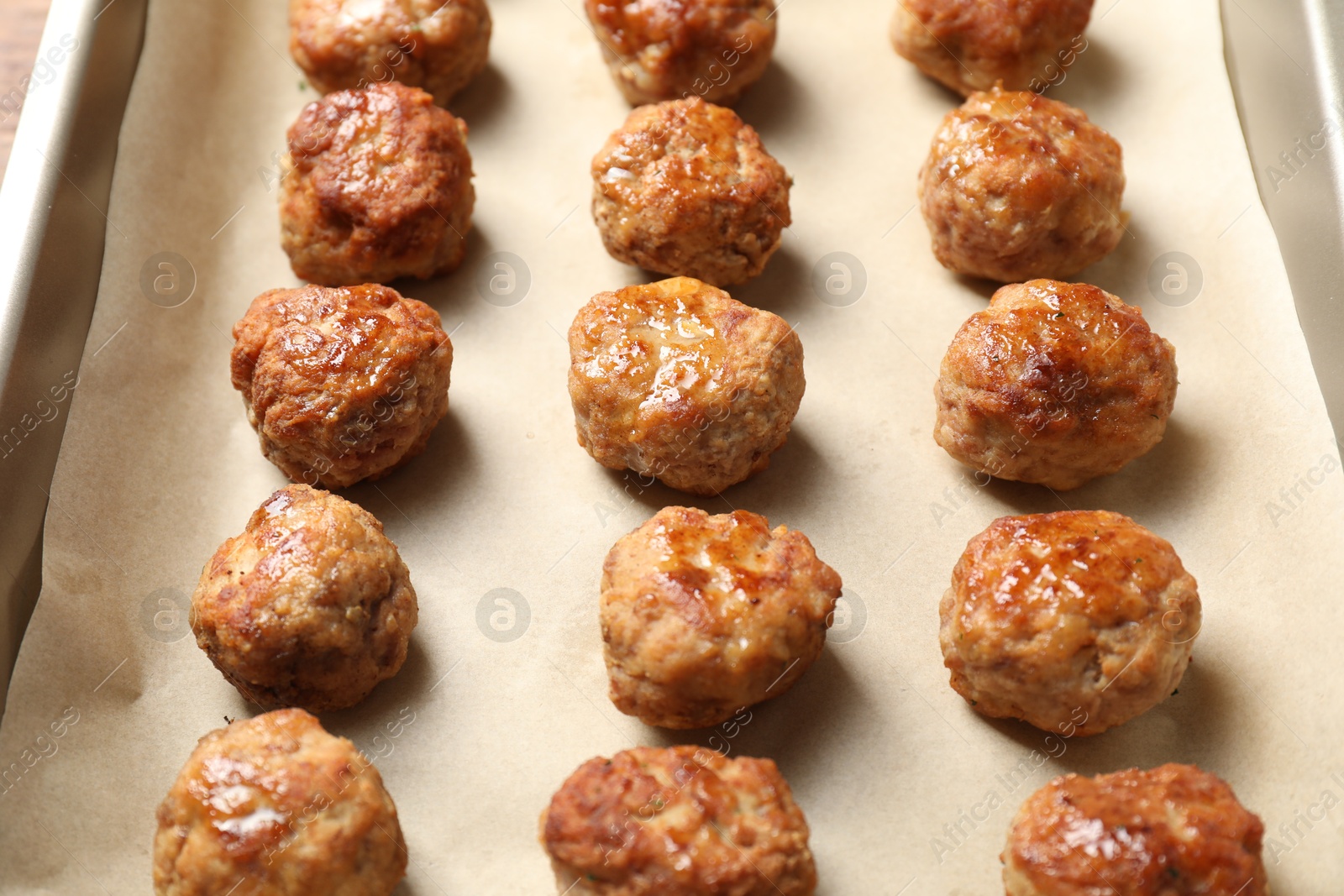 Photo of Many delicious meatballs on parchment in baking dish