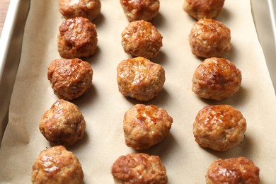 Photo of Many delicious meatballs on parchment in baking dish