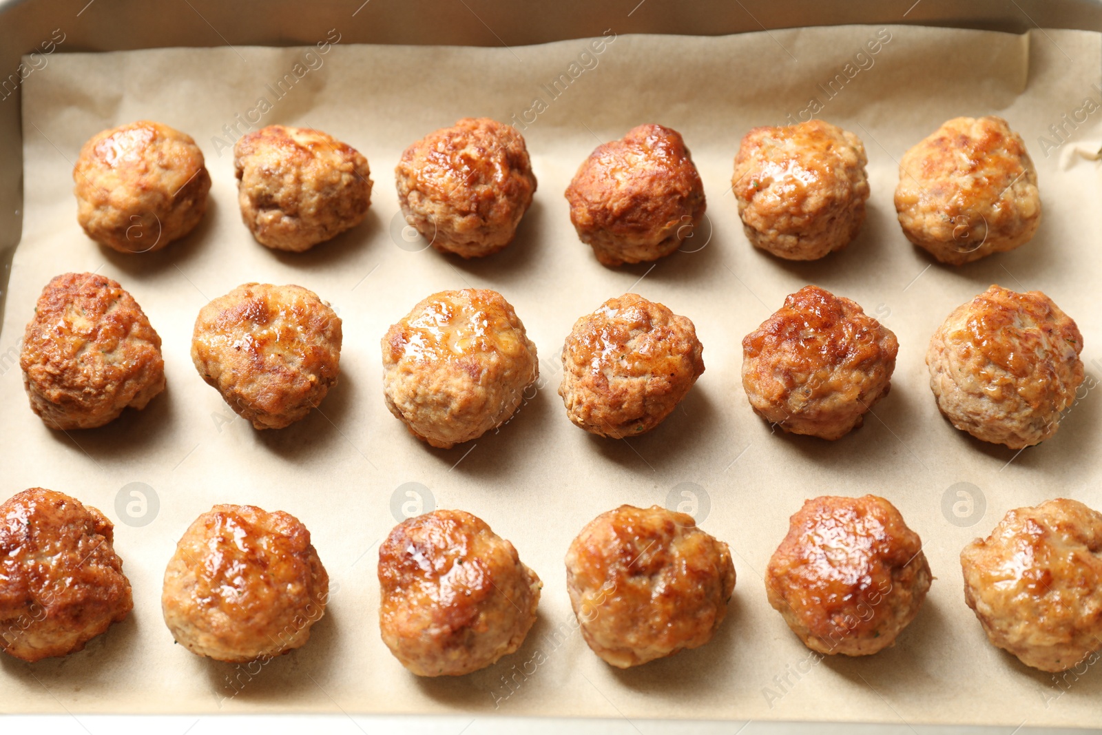 Photo of Many delicious meatballs on parchment in baking dish, above view