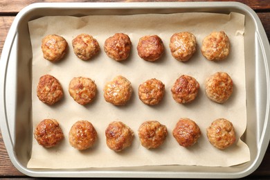 Photo of Many delicious meatballs in baking dish on wooden table, top view