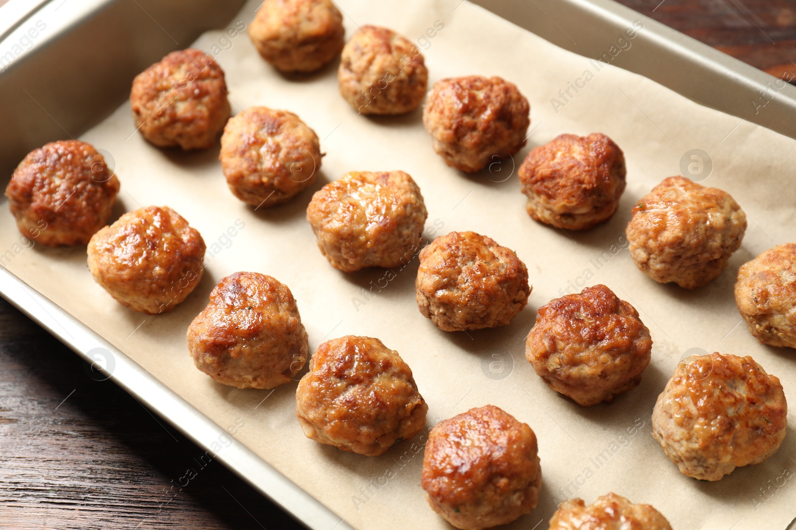 Photo of Many delicious meatballs in baking dish on wooden table, closeup