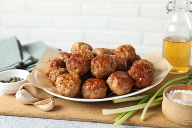 Photo of Many delicious meatballs, green onion, garlic, oil and spices on light textured table, closeup