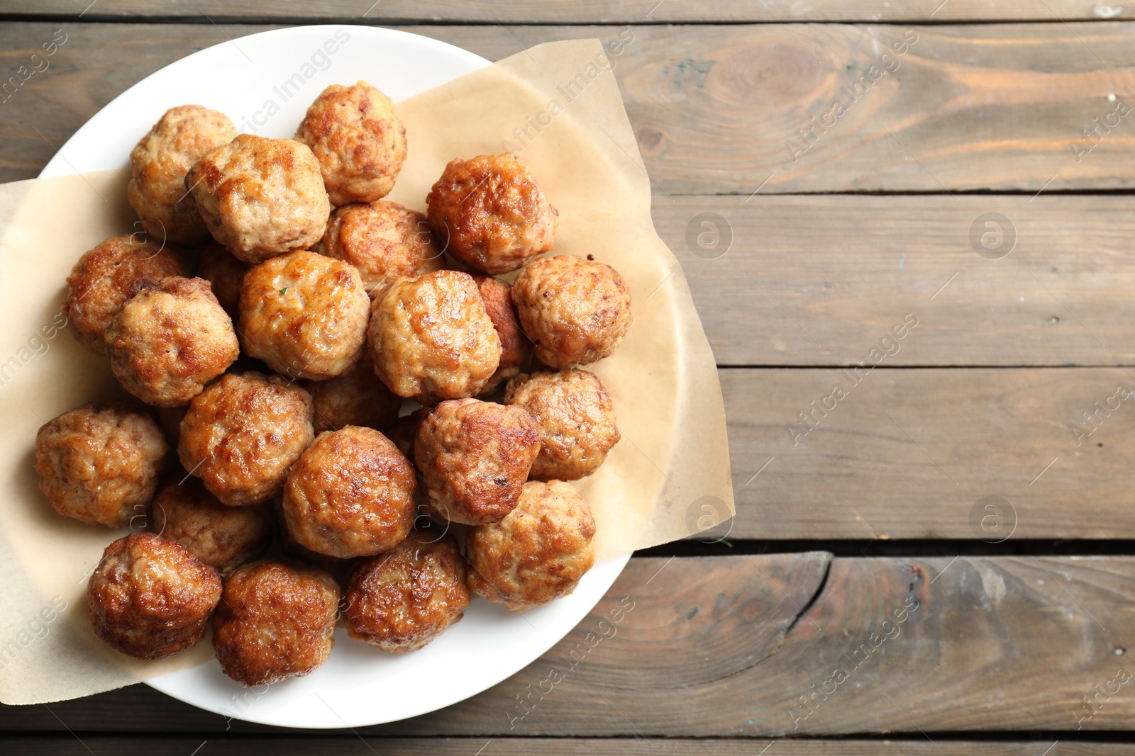 Photo of Many delicious meatballs on wooden table, top view. Space for text