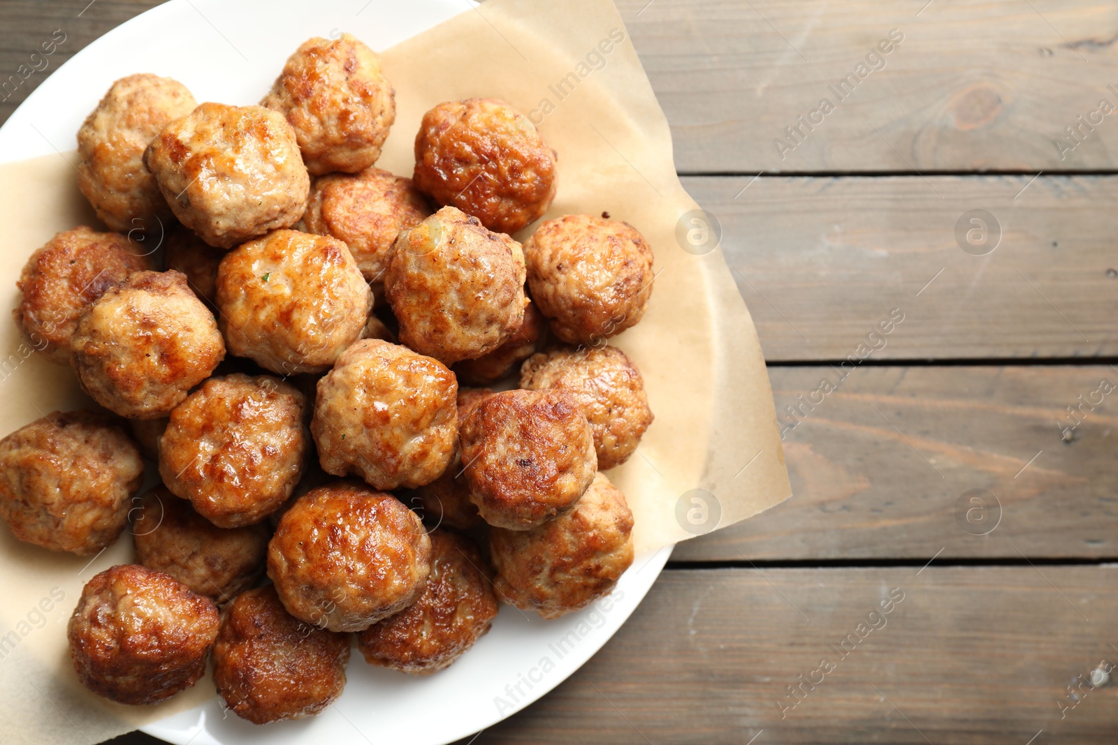 Photo of Many delicious meatballs on wooden table, top view. Space for text