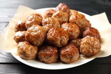 Photo of Many delicious meatballs on dark wooden table, closeup