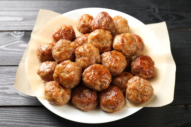 Photo of Many delicious meatballs on dark wooden table, closeup