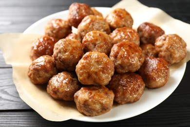 Photo of Many delicious meatballs on dark wooden table, closeup