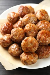 Photo of Many delicious meatballs on dark wooden table, closeup