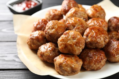 Photo of Many delicious meatballs on dark wooden table, closeup