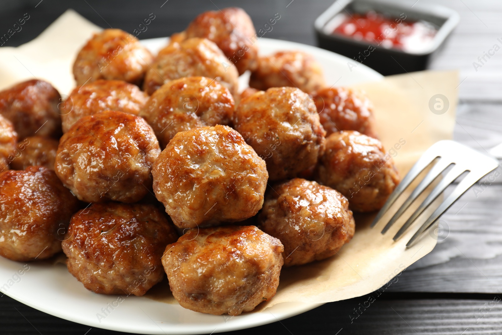 Photo of Many delicious meatballs on dark wooden table, closeup