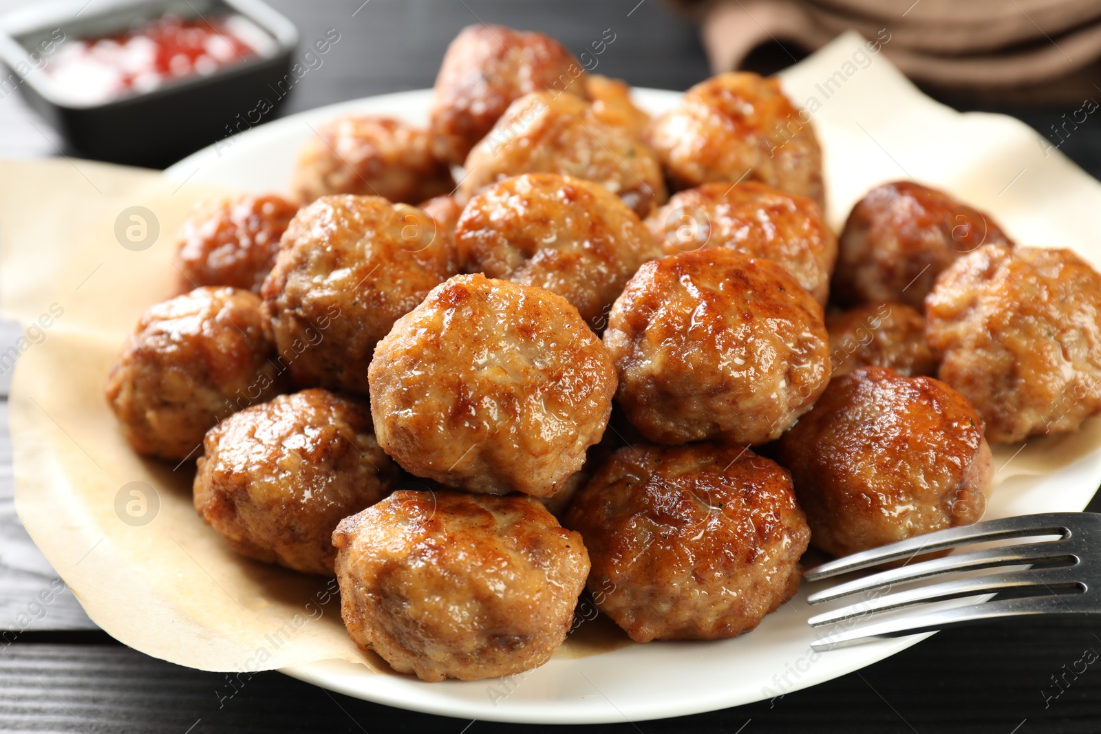 Photo of Many delicious meatballs on dark wooden table, closeup