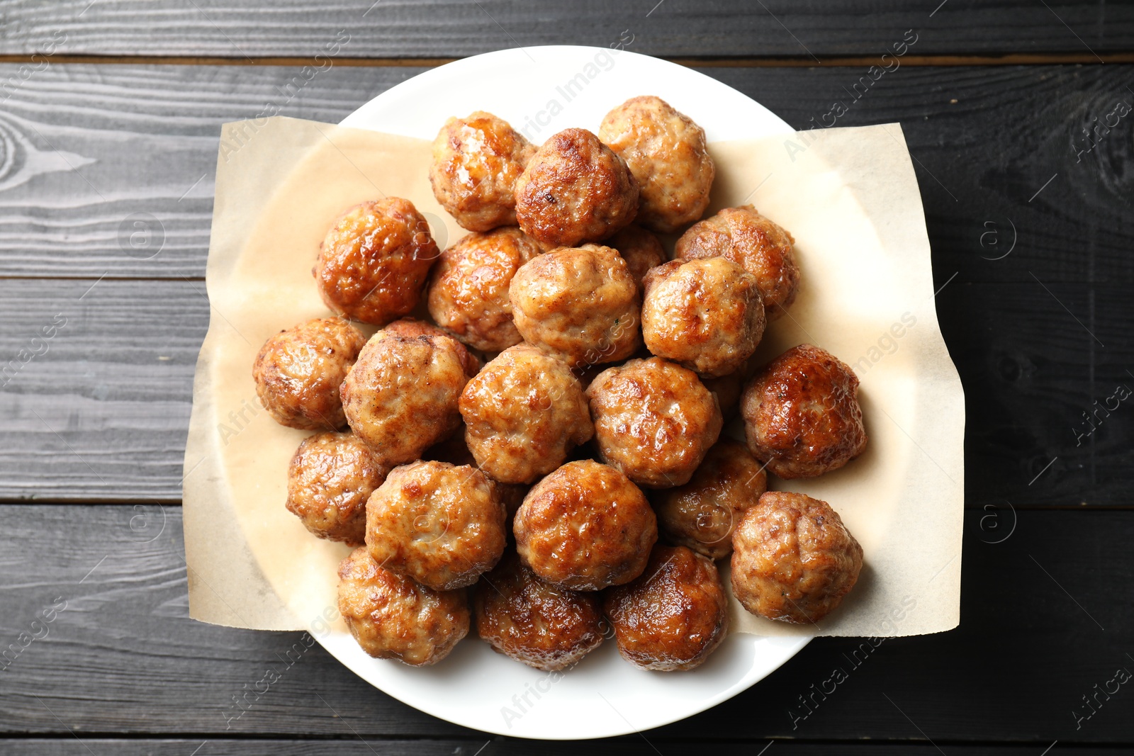 Photo of Many delicious meatballs on dark wooden table, top view