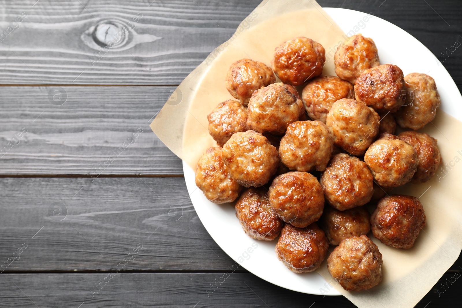 Photo of Many delicious meatballs on dark wooden table, top view. Space for text