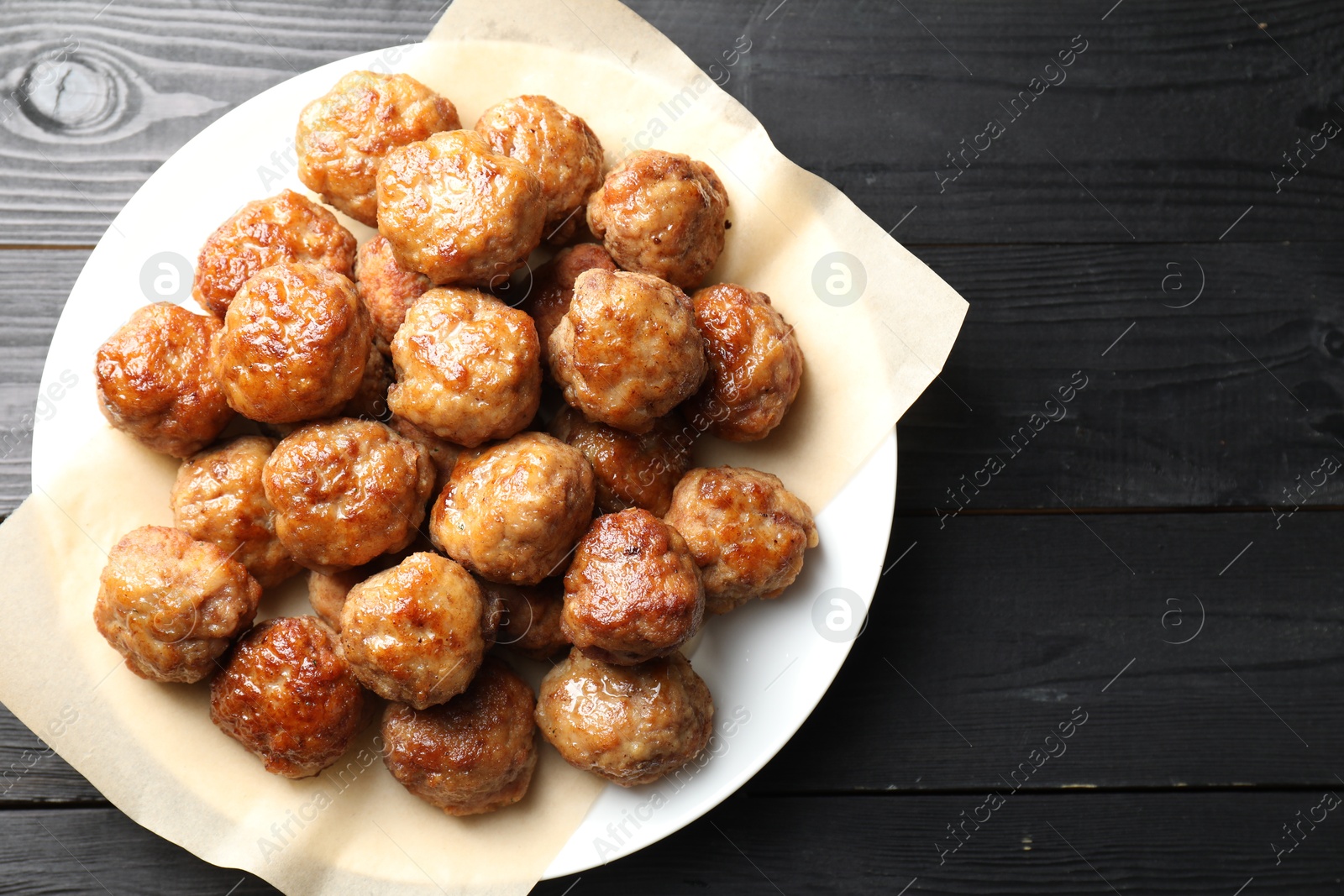 Photo of Many delicious meatballs on dark wooden table, top view. Space for text