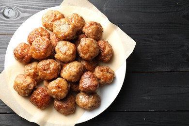 Photo of Many delicious meatballs on dark wooden table, top view. Space for text