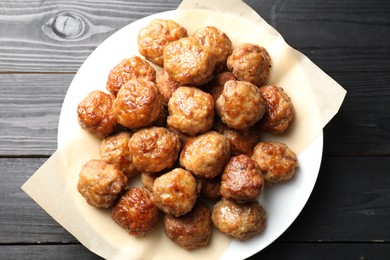 Photo of Many delicious meatballs on dark wooden table, top view