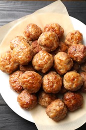 Photo of Many delicious meatballs on dark wooden table, top view