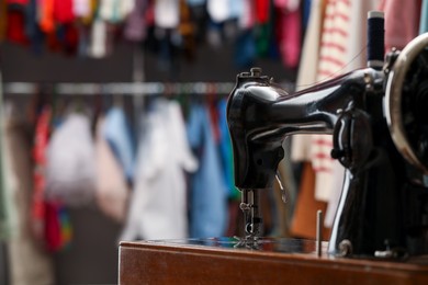 Photo of Vintage sewing machine with thread in workshop, closeup. Space for text