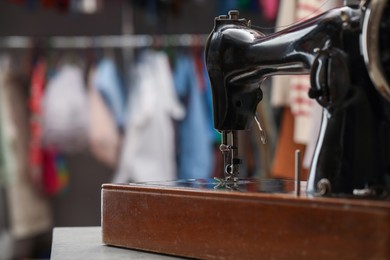 Photo of Vintage sewing machine with thread on table in workshop, space for text