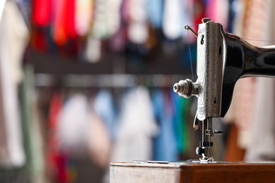 Photo of Vintage sewing machine with thread on blurred background, closeup. Space for text