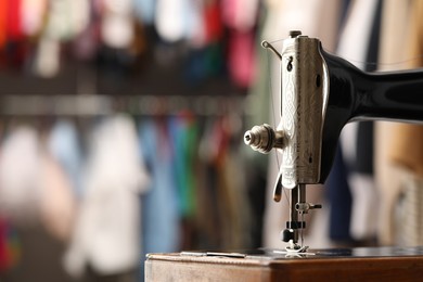 Photo of Vintage sewing machine with thread on blurred background, closeup. Space for text