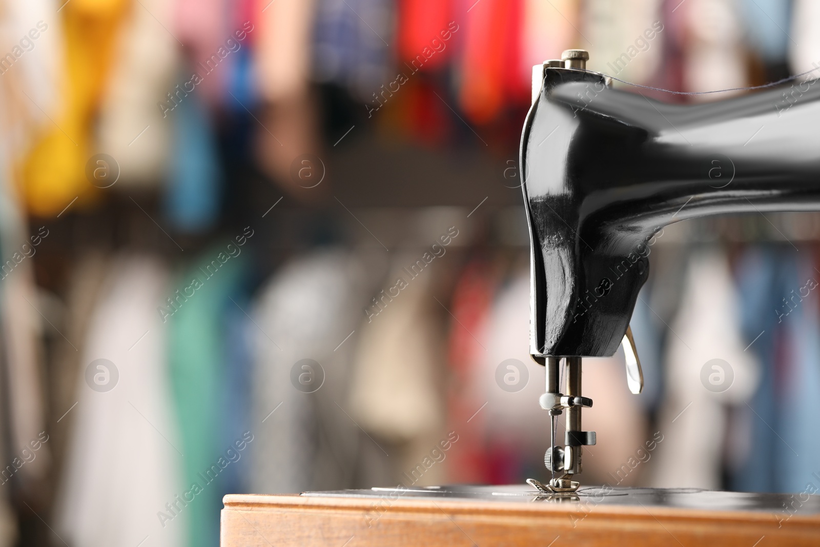 Photo of Vintage sewing machine with thread on blurred background, closeup. Space for text