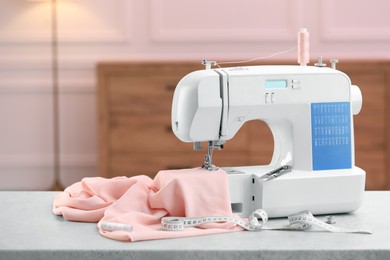 Photo of Sewing machine with fabric and other supplies on white table in workshop