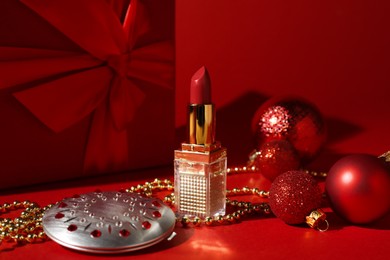 Christmas present. Cosmetic products, gift box and festive decor on red background